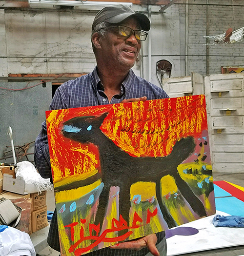 Charlie Lucas holds a piece of his artwork while posing for picture.