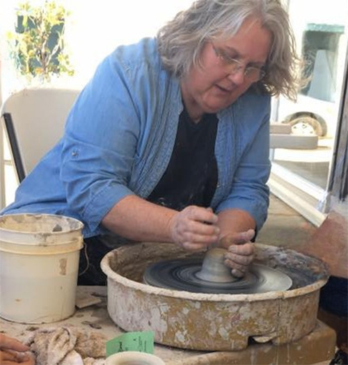 Jo Taylor leaning over pottery wheel